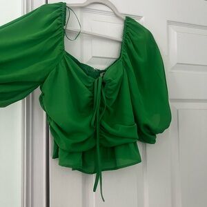 A green blouse that zips in the back and has a tie at the top.
